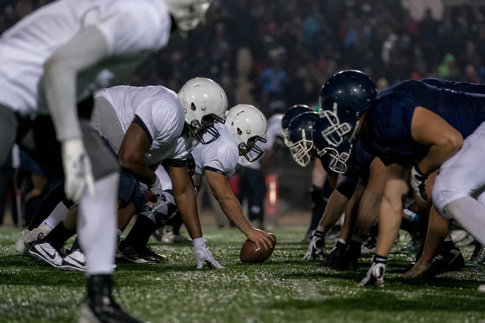 Adult American football players at the line of scrimmage during the snap