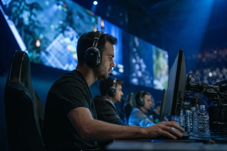 Adult esports players competing at PCs on an arena stage