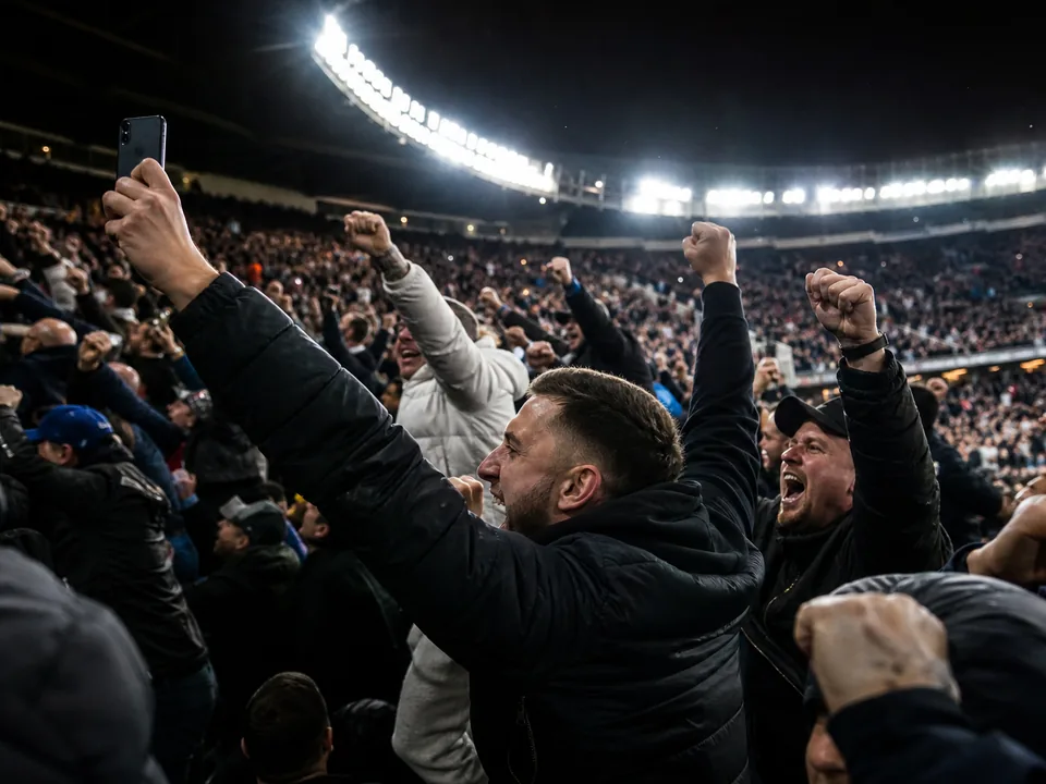 Fans in stadium stands celebrating a goal at night
