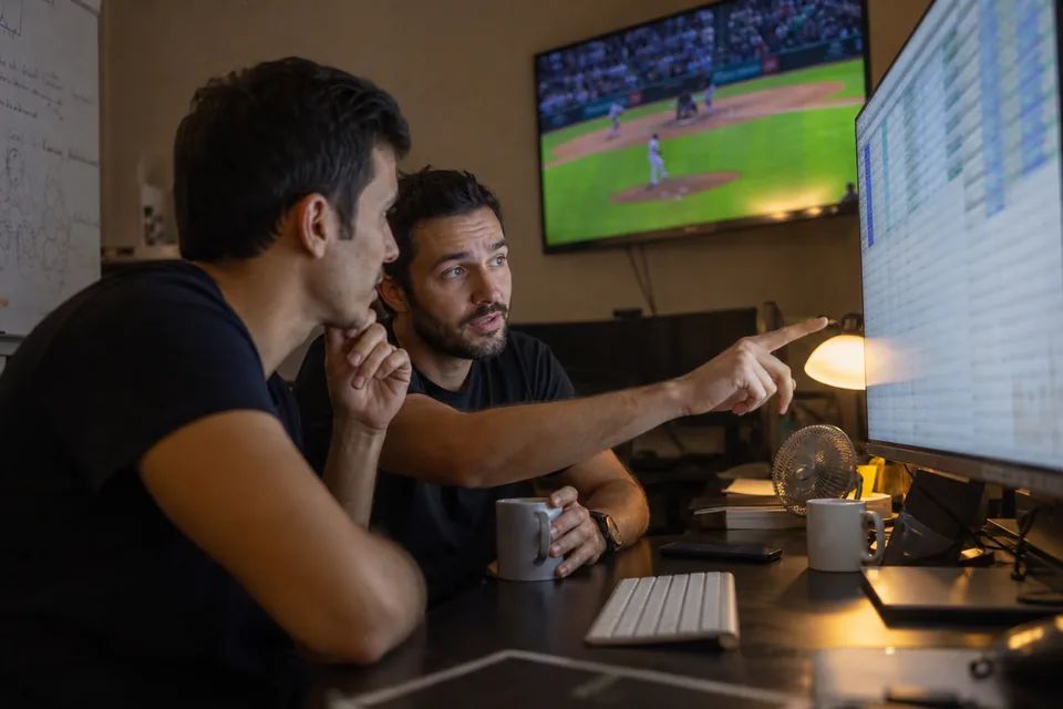Two developers at an odds comparison site reviewing a live price feed on a wide monitor