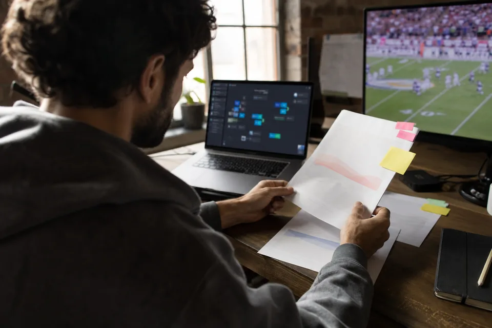 Engineer at a sports data startup comparing two odds API vendor quotes next to a laptop